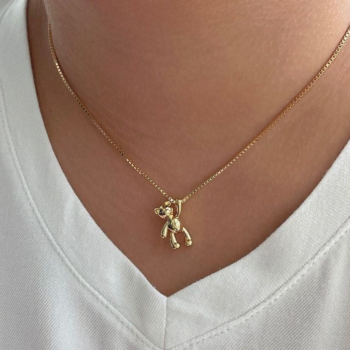A gold-toned stainless steel necklace with a pendant shaped like a teddy bear.